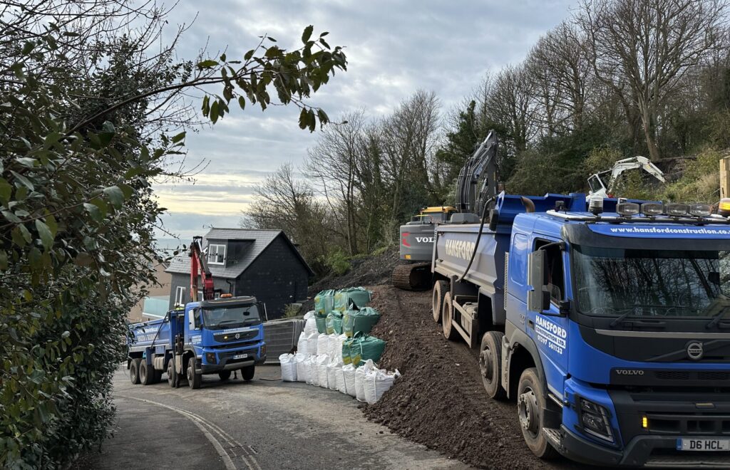 Grab lorry transporting material during emergency groundworks and landslip repair in Lyme Regis