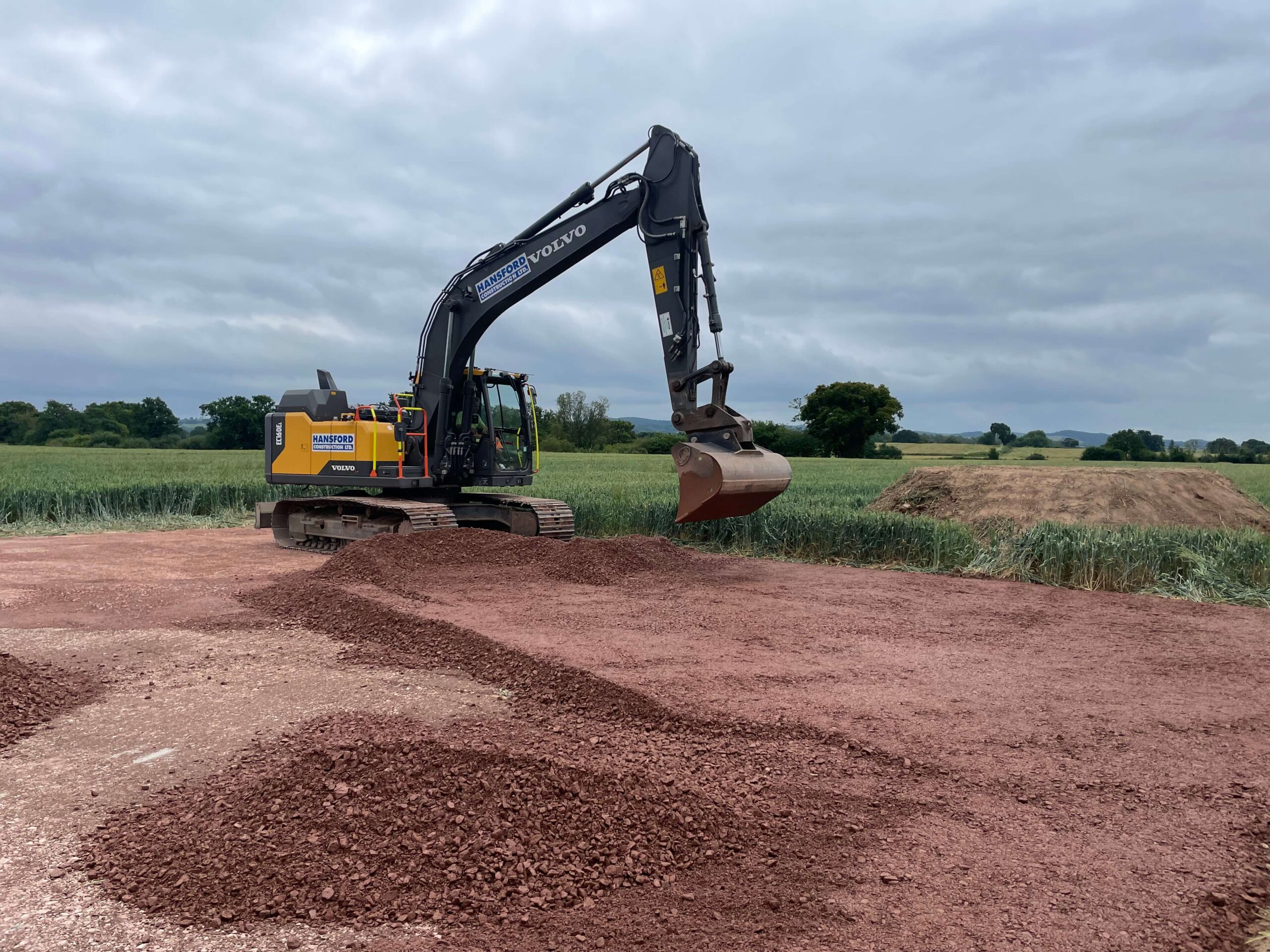 Excavator grading soil for site preparation in Devon